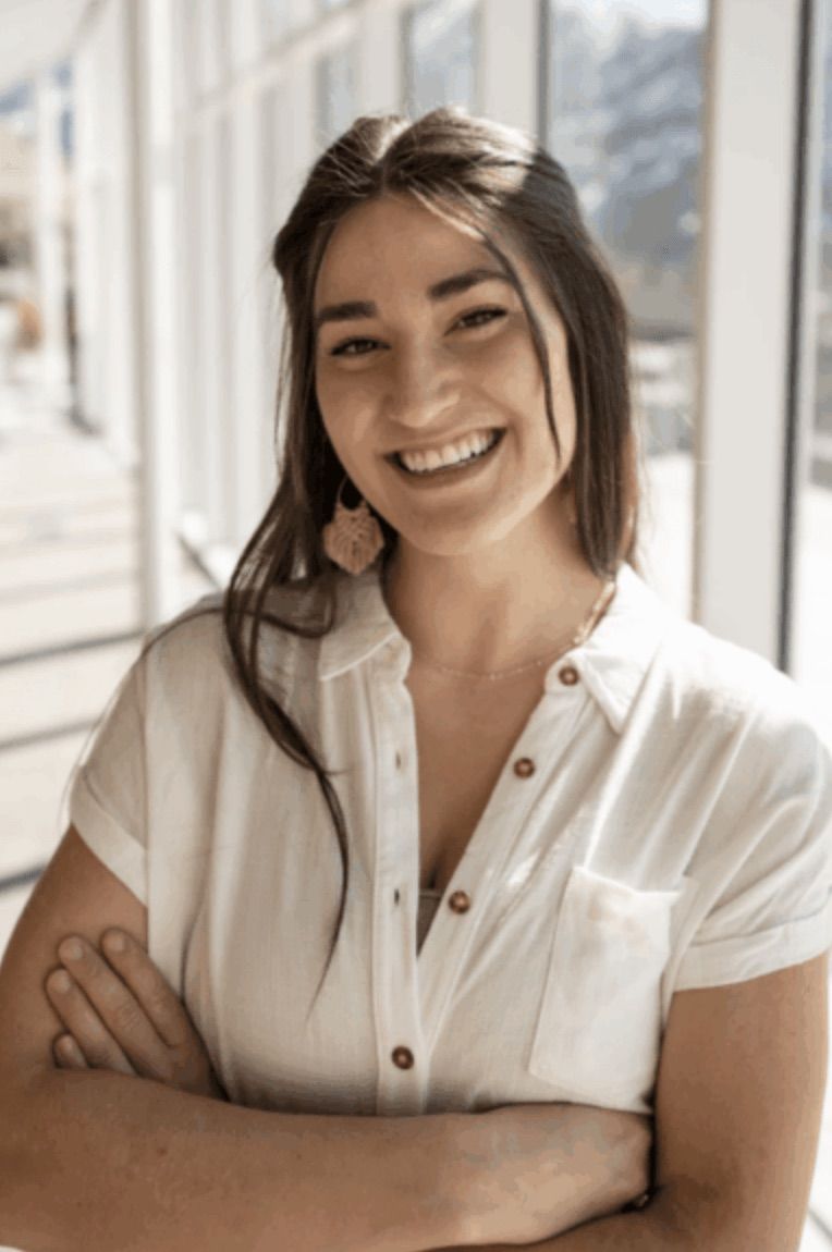 Mariah O'Donnell smiling with her arms crossed in a sunlit hallway.